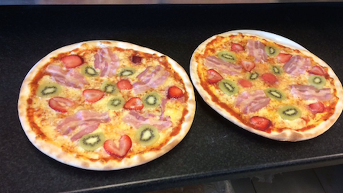På den här pizzan är det kiwi, jordgubbar, bacon och beanaisesås.